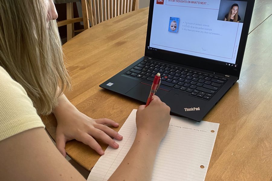 student facing away from camera writing on a piece of paper