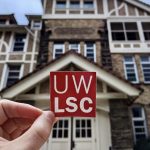 A sticker that reads, "UW LSC," is held up in front of Hiram Smith Hall