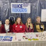 LSC students Victoria Rubinetti, Abby Cortichiato and Catie Stumpf sit at a table at the Wisconsin Fishing Expo in Oshkosh with LSC Professor Brett Shaw